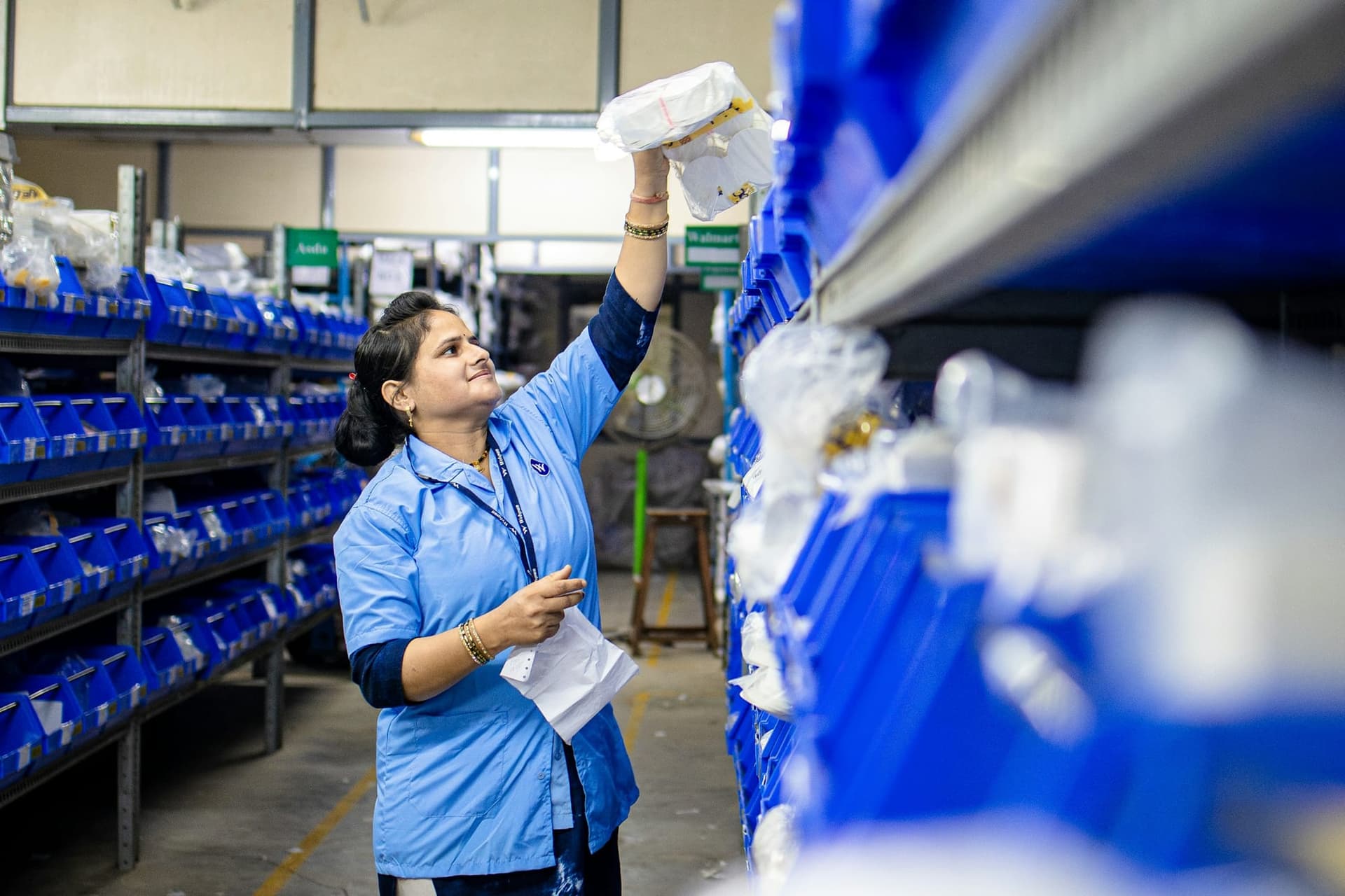 Warehouse operative picking consumer goods from a stocked shelf