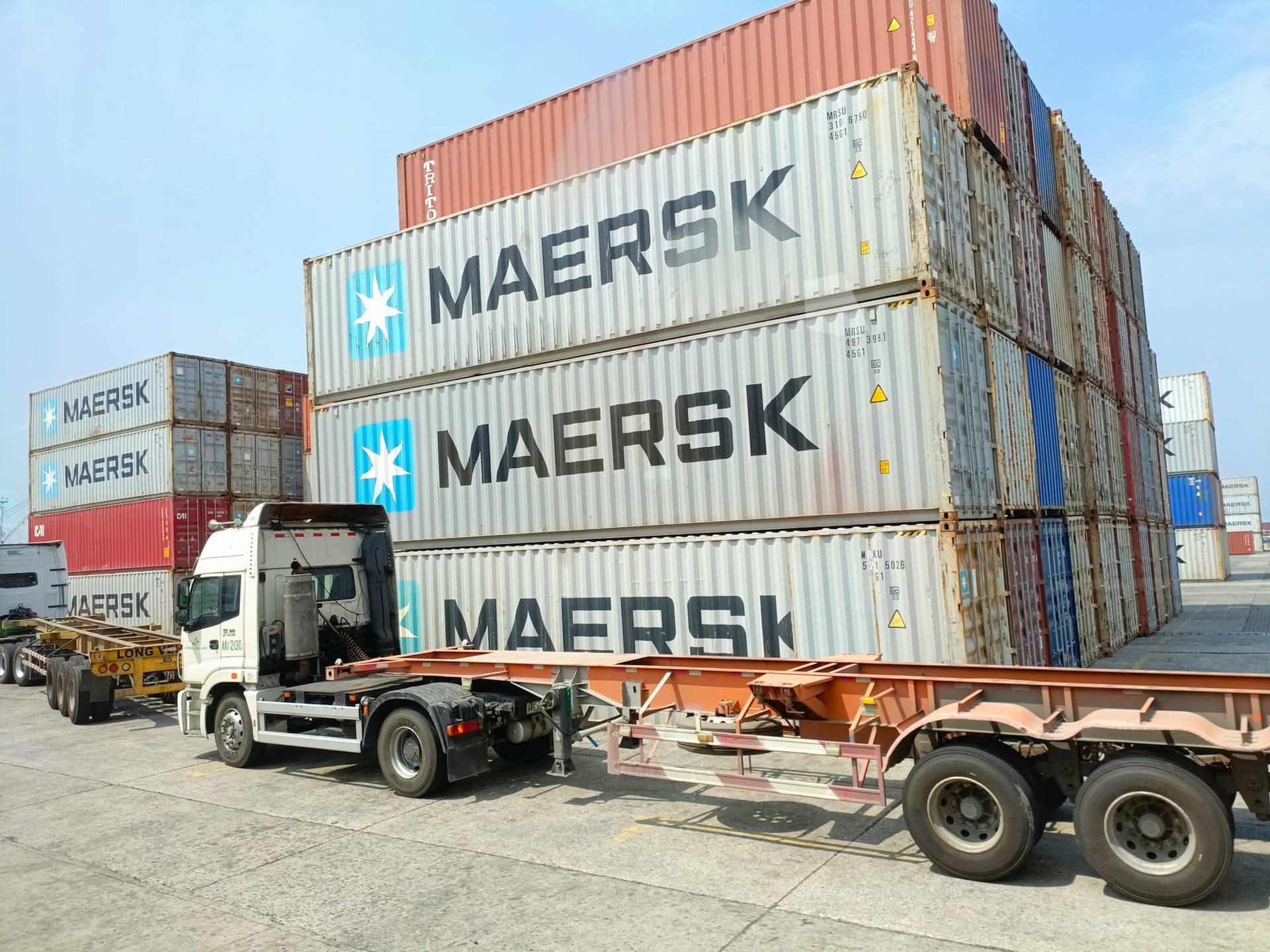 Haulage truck beside stacked shipping containers in a freight yard