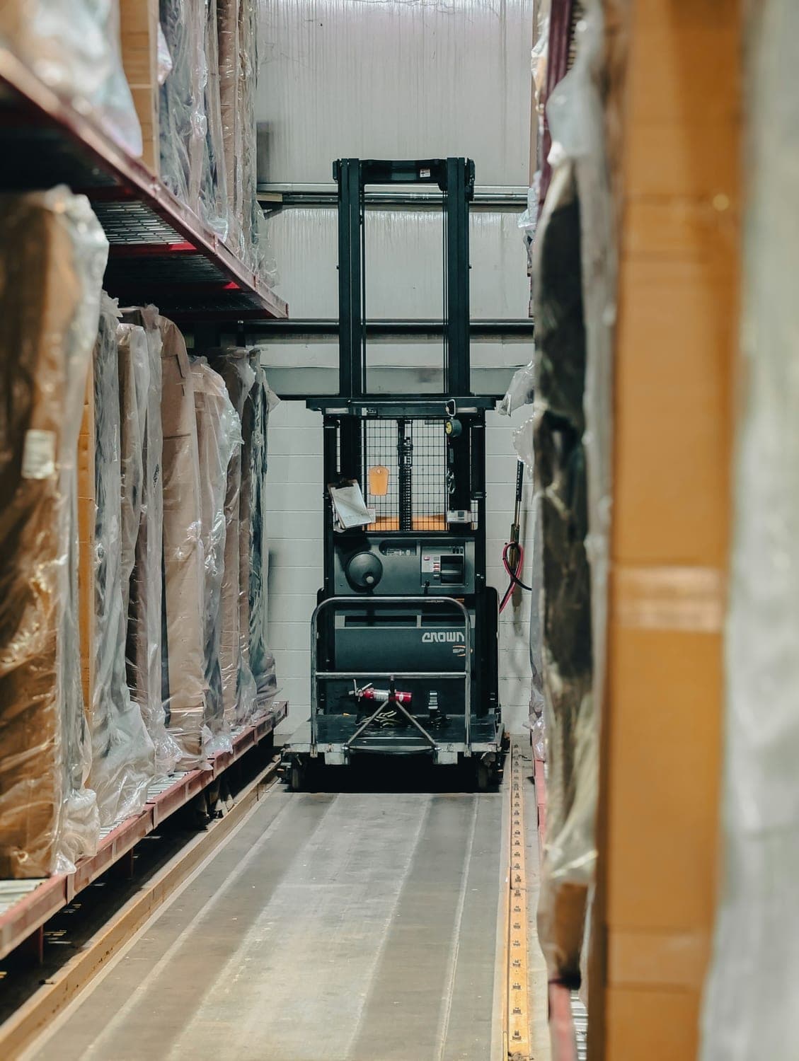 Forklift moving between shrink-wrapped pallets being assembled for a shipment