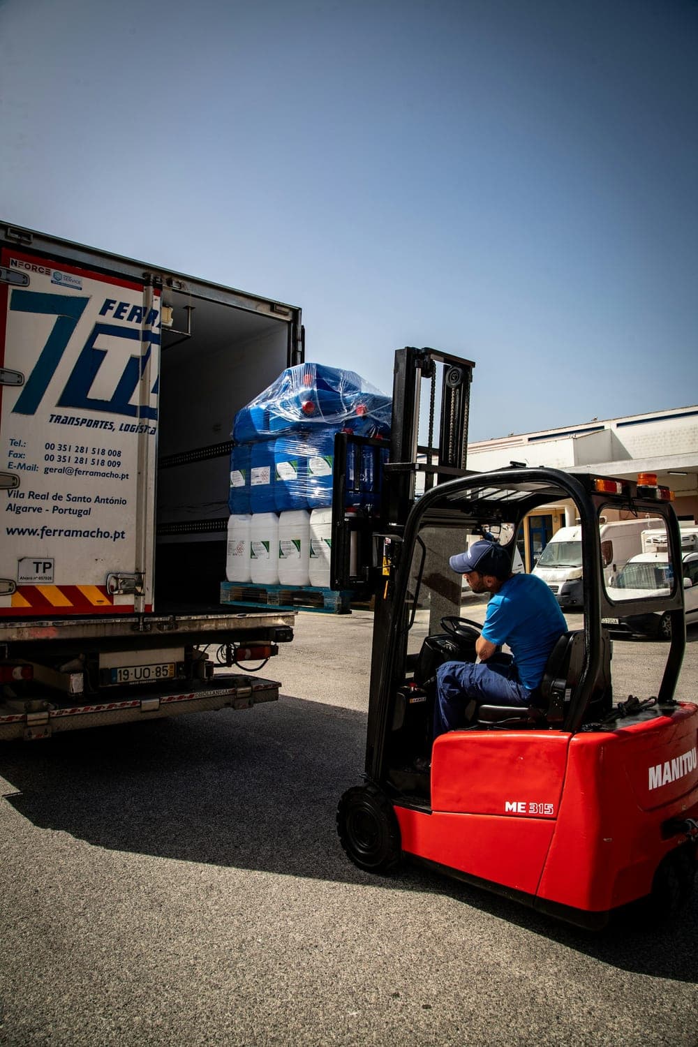 Forklift loading a shrink-wrapped pallet of consumer goods into a freight truck